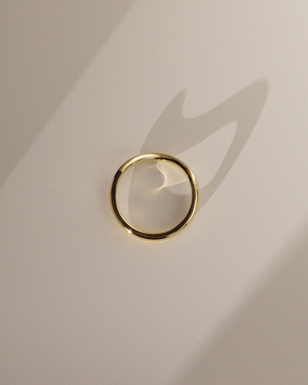 Plain curved wedding band with a smooth polished finish β minimalist contour design in gold, perfect for pairing with solitaire or vintage engagement rings.