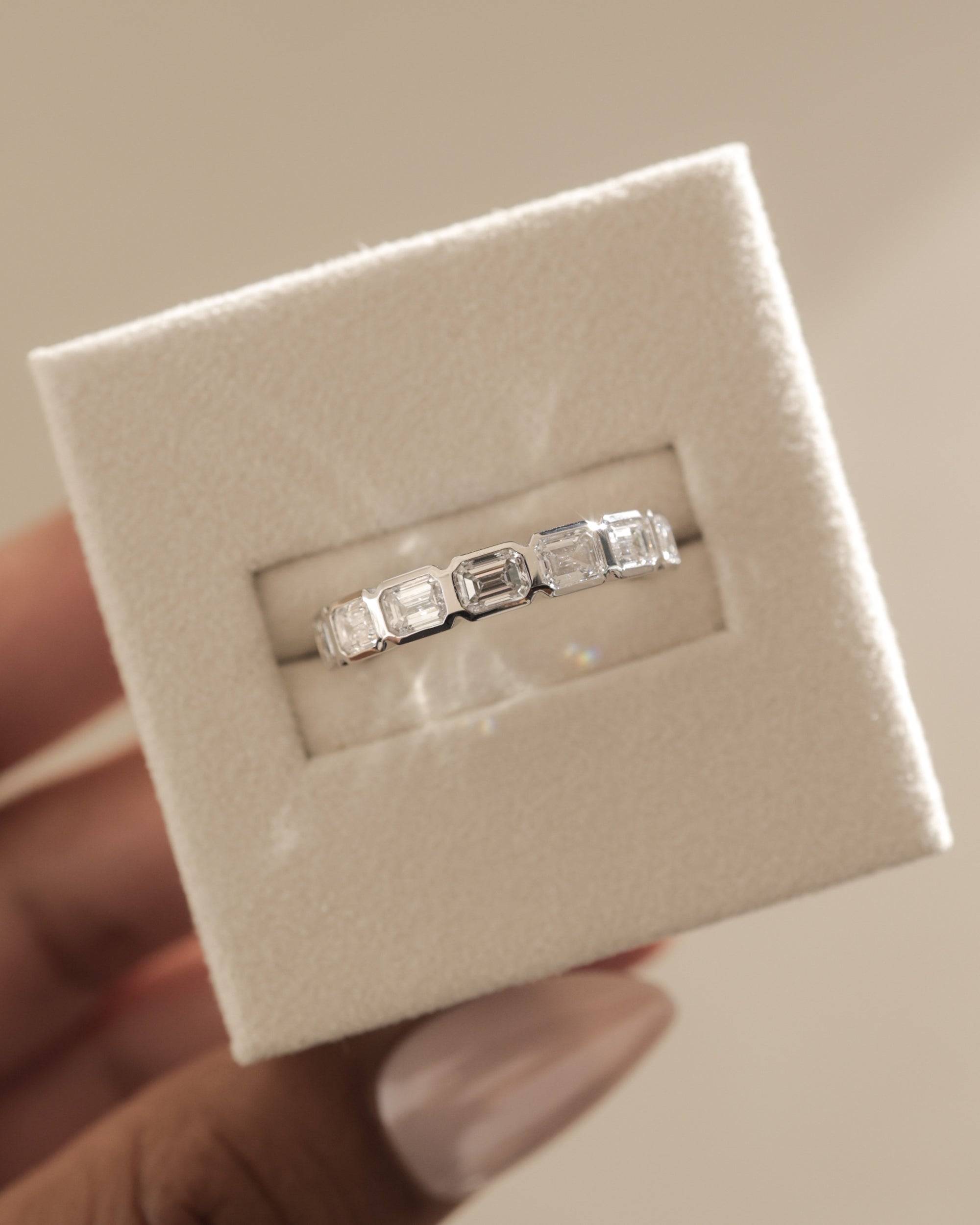 1.05 TCW emerald cut moissanite wedding band with bezel setting – sleek and sophisticated gold ring featuring step-cut stones, perfect for modern bridal or stacking style.